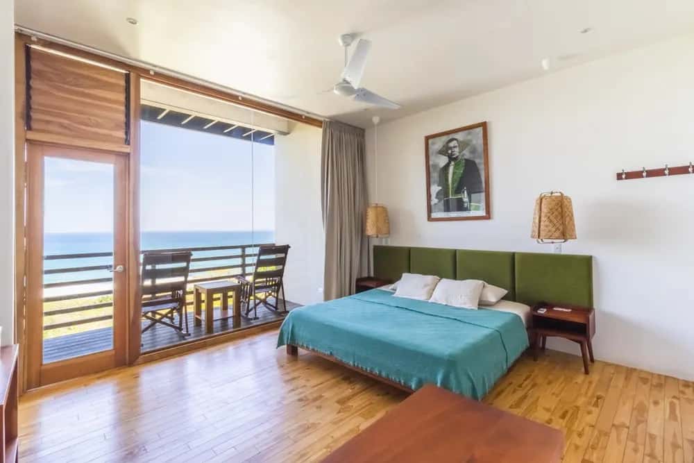 Bedroom with turquoise bedding and ocean-view balcony — Barefoot Chateau 3