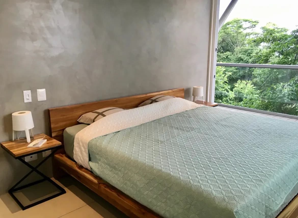 Bedroom with broad window overlooking trees — Villa Dos Vistas
